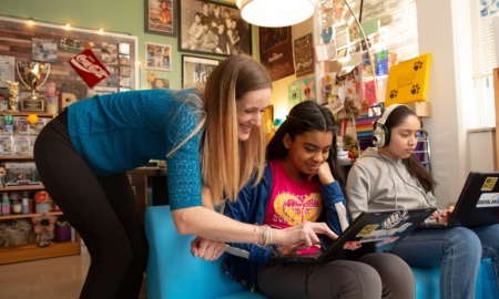 2024 national educational technology plan: female teacher helps a student working on laptop