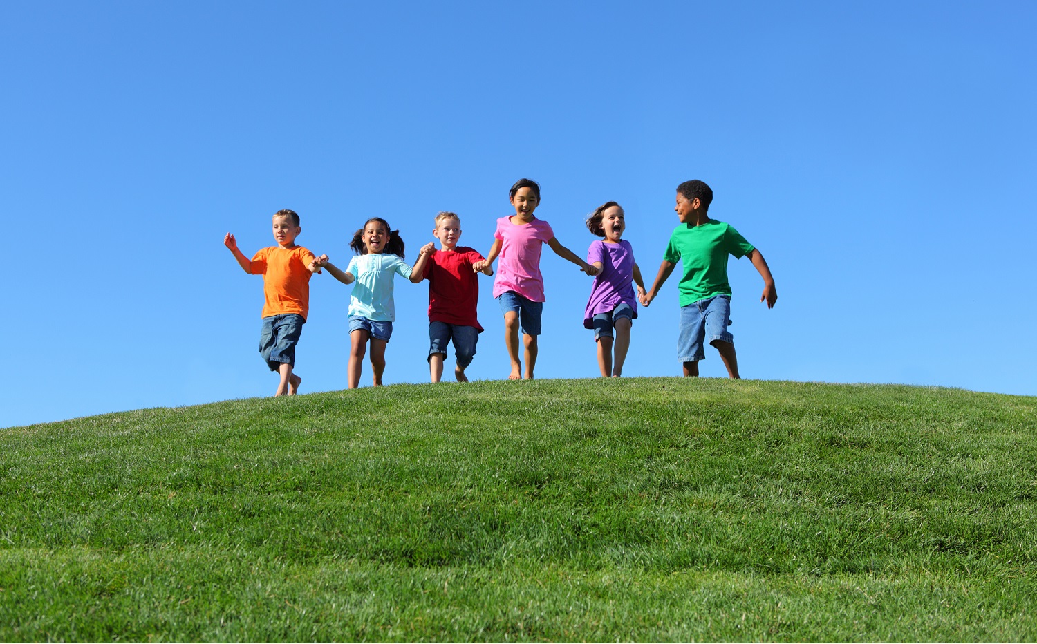 child opportunity report: happy children running over grassy hilltop towards camera