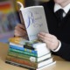 Activism grows in response to school book bans: person reading book atop stack of other books