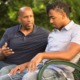 mentoring for at-risk youth: older bald black man talks to young man on park bench