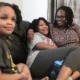 Autism now more common among Black, Hispanic kids in US: black family sitting on couch with mother hugging daughter while smiling