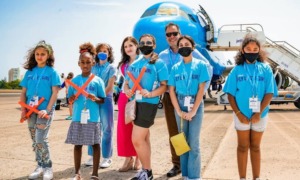 aviation education grants: group of girls in bright blue shirts standing in front of plane on tarmac