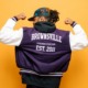 Brooklyn BIPOC community grants: Black youth on solid brightly colored background in jacket flexing arms