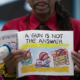 Children's Books Gun Violence: Black man in red shirt holfing a book titled, "A Gun is Not the Answer"