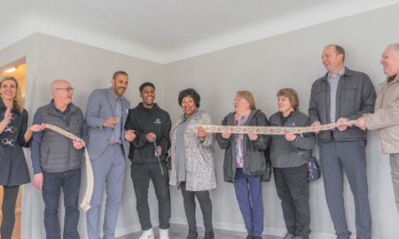 Can affordable housing make afterschool field fairer for workers: Group of people standing in empty room of house holding a banner while smiling