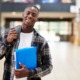 A living stipend for disadvantaged college students: black, male college student smiles while holding folder and walking with backpack on