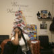 Woman in white top holds hand to forehead in front of white tabletop Christmas tree.