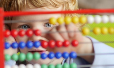 San Diego early childhood grants: young caucasian boy using colorful abacus