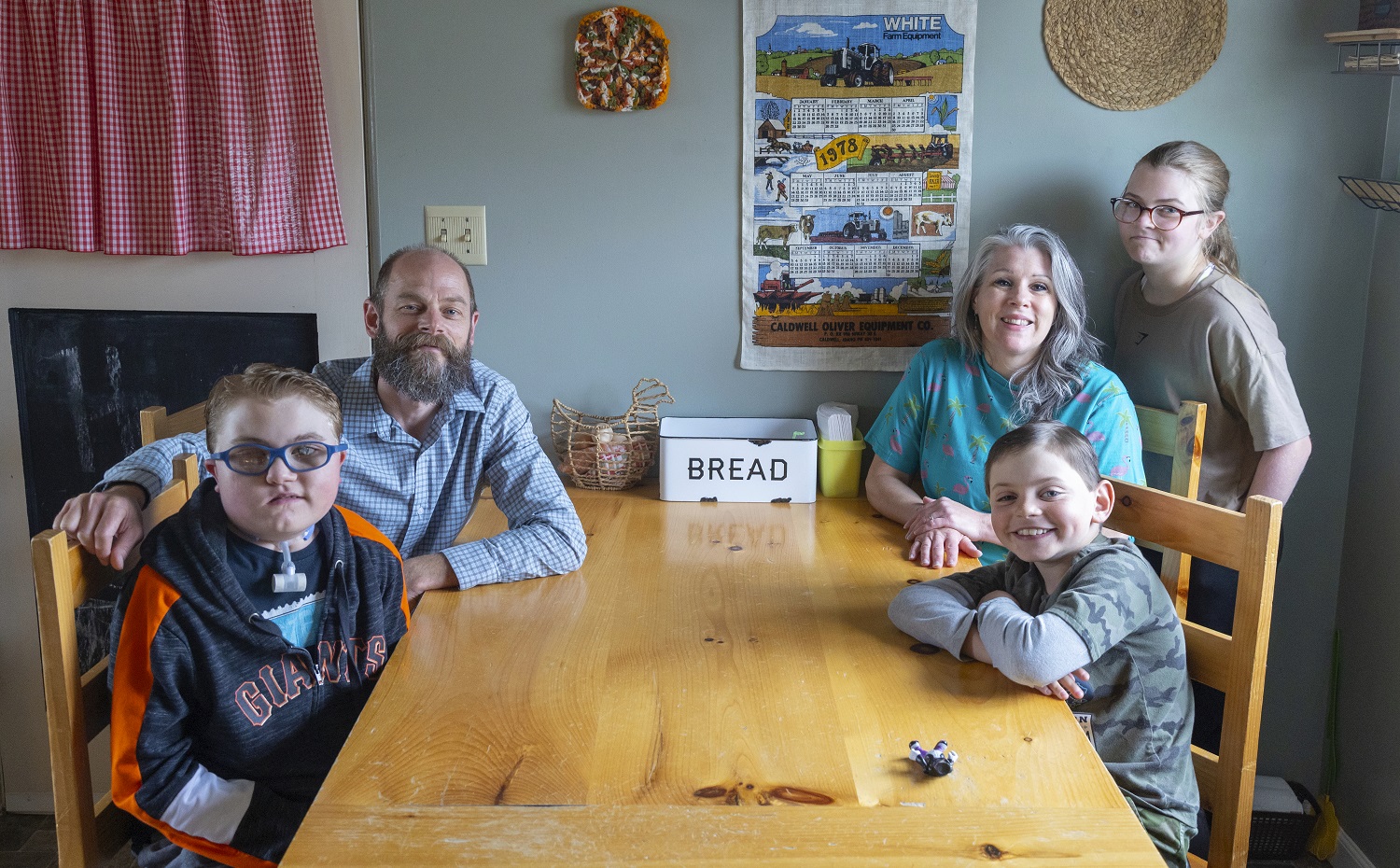 Families worry over future of medicaid caregiver payments: family sitting at wooden kitchen table smiling