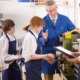 High school skilled trades education educator award grants: Teacher demonstrating lathe to high school pupils in metalwork class