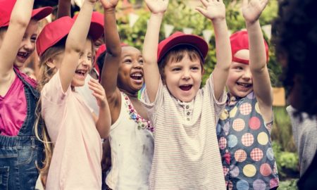 youth summer camp and learning program award: happy children raising hands outside