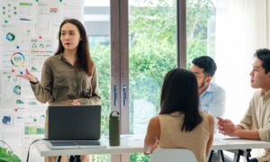 climate change, how colleges can become 'living labs' for combating climate change: female student gives presentation to group of other students at table