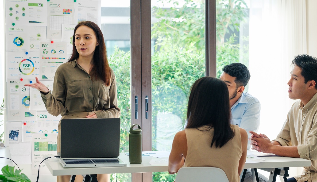 climate change, how colleges can become 'living labs' for combating climate change: female student gives presentation to group of other students at table