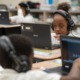 Illinois lawmakers pass 2025 budget: young black female student working on laptop with headphones on in school