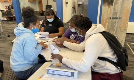 Oklahoma basketball team afterschool data, analytics program: four black youths at a table working