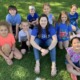 SEL - A person with long hair and children sit on the grass