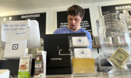 youth with autism and epilepsy transition to adulthood: young man with disability in blue shirt working at counter of store