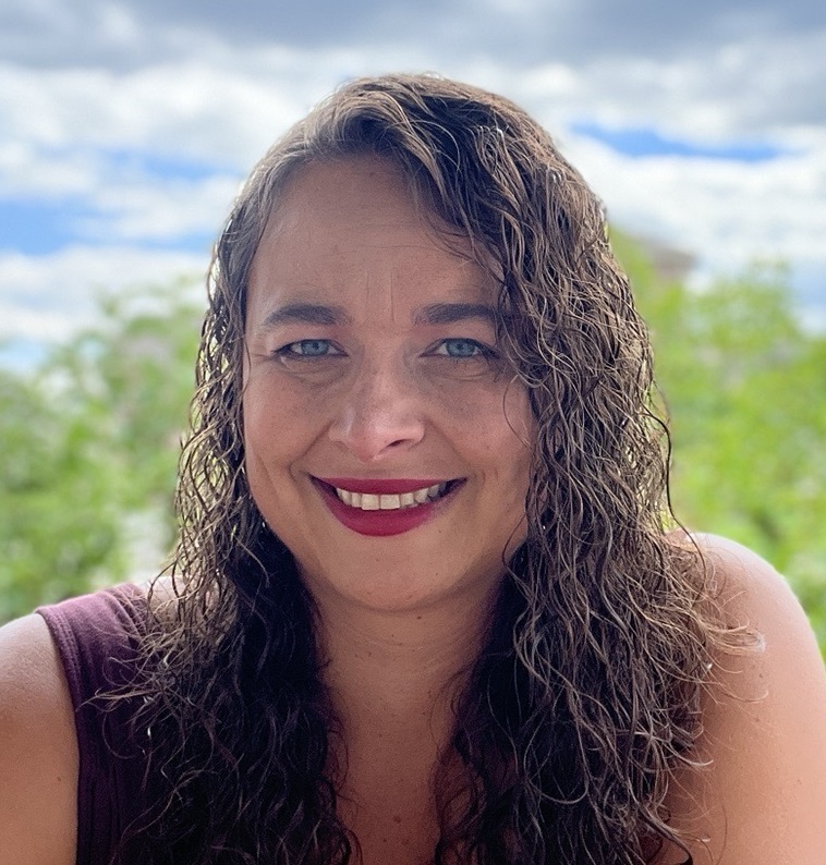 Katherine Plog Martinez: white woman with long, dark curly hair smiling outside