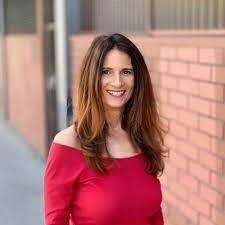 Mara Ziegler foster care youth: white woman with long dark hair wearing red standing outside near brick wall