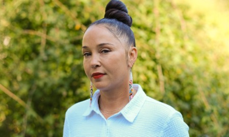 Michaela Pommells headshot: woman with dark hair up in bun and colorful earrings standing outdoors