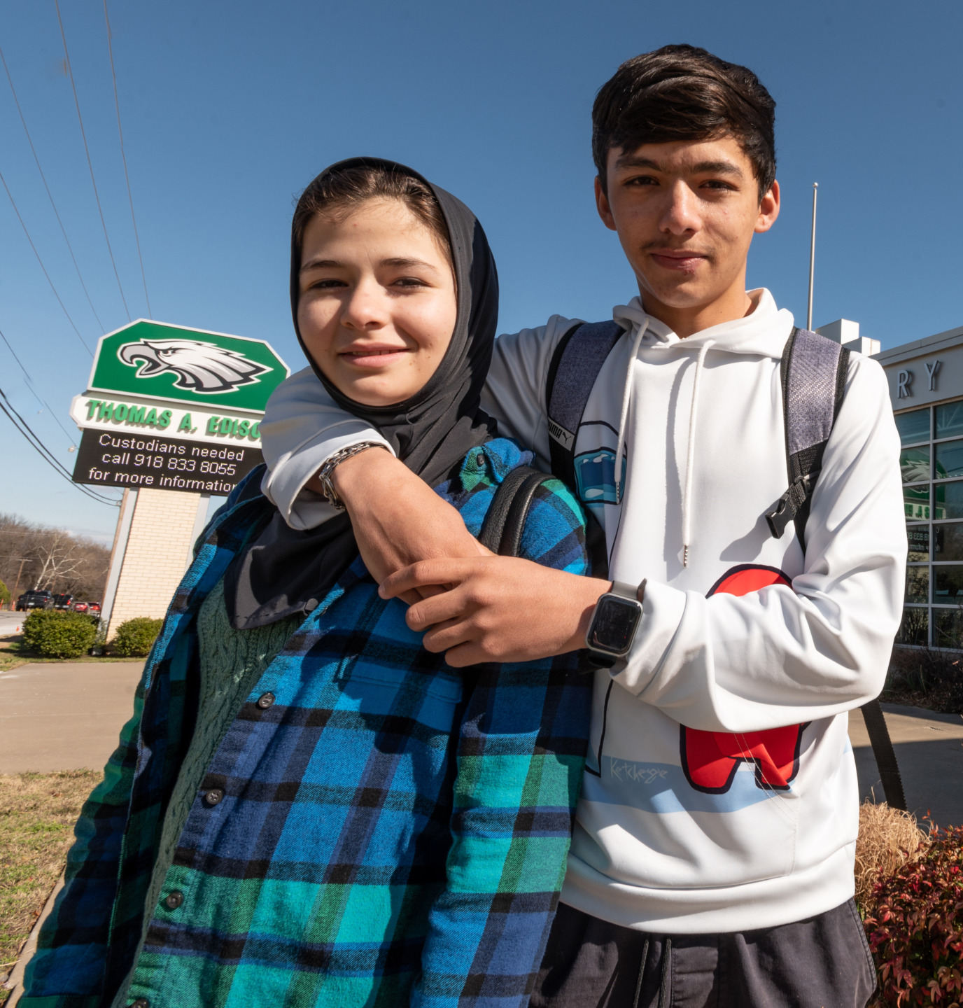 Refugee youth: Two young people stand in front of a stone and glass building