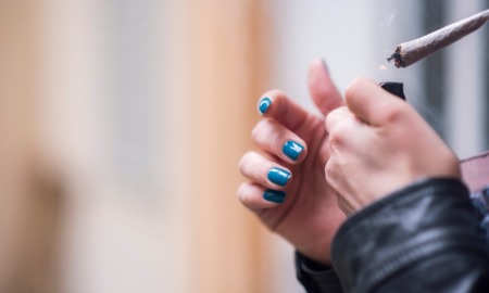 youth drug use survey results: female hands with painted fingernails lighting up a joint