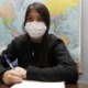 new approach to teaching race divides New Mexico: young Hispanic female student with mask on taking notes with world map on wall behind her