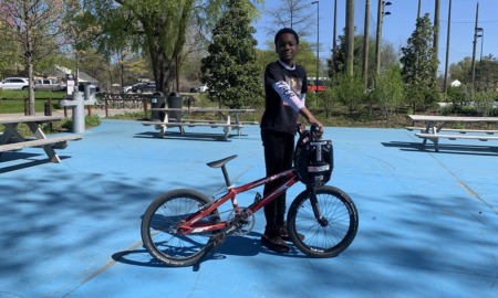 New BMX program teaches North Tulsa kids about bikes, racing and resilience: young black kid poses with his BMX bike outdoors