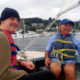 homelessness: 2 men with life jackets on in boat, smiling.