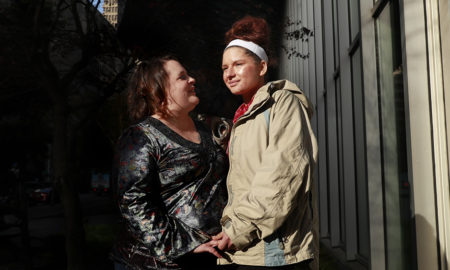 mental health: Woman holds hands with younger woman who is looking off to side.