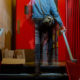 homeless: Person in jean jacket climbing stairs; tray of filled brown bags on landing