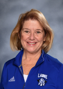 School triage training: Headshot of xhort-haired blonde woman in dark blue shirt smiling into camera.