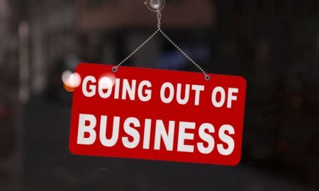 jobs: Close-up on a red closed sign in the window of a shop displaying the message Going out of business.