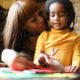 Foster care racism: Black woman with young Black child sitting at table doing homework.