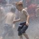 Summer camps hit with COVID outbreaks, are schools next?: picture of children playing in water on hot day