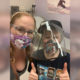 Disabled Speak Out: young boy in dark baseball cap and black t-sirt with plastic face shield and mask sits with blonde woman with face lanendar floral mask on hospital bed with medical gear in background.