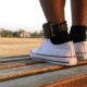 Juvenile diversion and probation: Closeup of two feet wearing white tennis shoes and black socks with an ankle monitor on left ankle