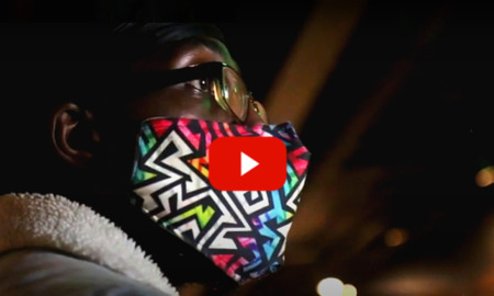 Gang-banger reform: Closeup profile of Kennebrew - Black man in dark-framed glasses wearing multi-color geometric print mask