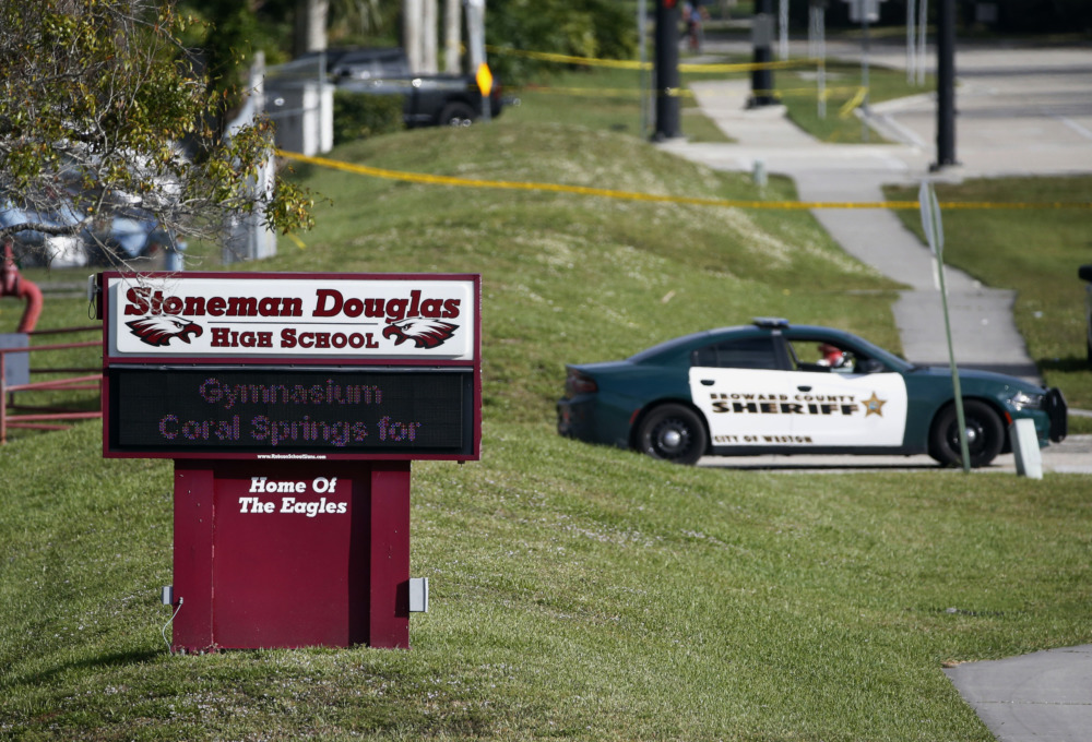 School triage training: Margory Stone Douglas High School sign on green lawn with police car in background