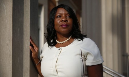 Merit scholarship racial inequities: Black woman with long black hair wearing white top and pearl necklace looks to her left