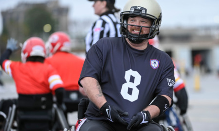 Wheelchair football: Several player in navt team shirt No. 8 and white helmet sits in a wheechair