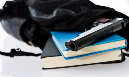 Guns in school: Hand gun and biiks sitting in open black backpack