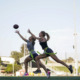 Girls' flag football: Two teen girls chasing football down playing field