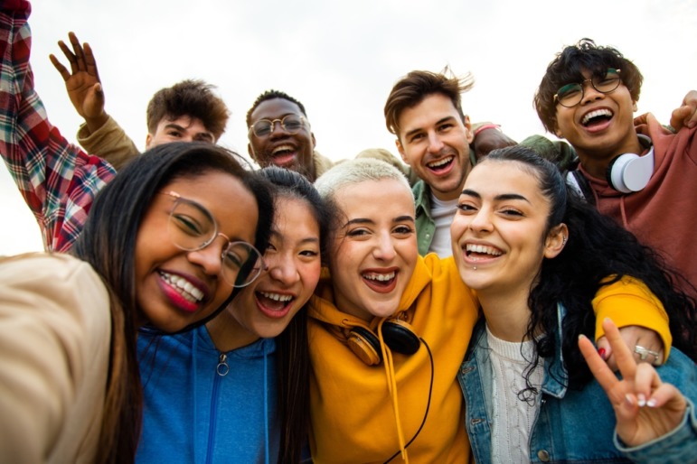 DEI in colleges: Group of nine tens stands crowded together to take a close-up selfie.