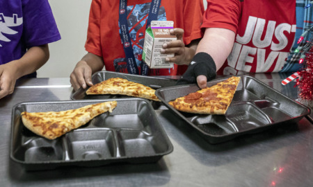 School lunches sugar: Closeup of three black sectioned lnnch trays with piece of pizza on each tray