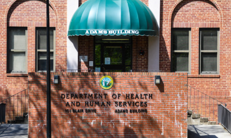 Foster care lawsuit: Red brick building with green entry stoop canopy and black letter signage "Department of Health and Human Services"