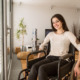 Reproductive Health Care: Dark-haired woman in ta shirt and vbrown pants sits in wheelchair in modern office waiting room