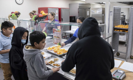 Hungry Kids: Elementay students stand in line adding food to their food trays in school cafeteria