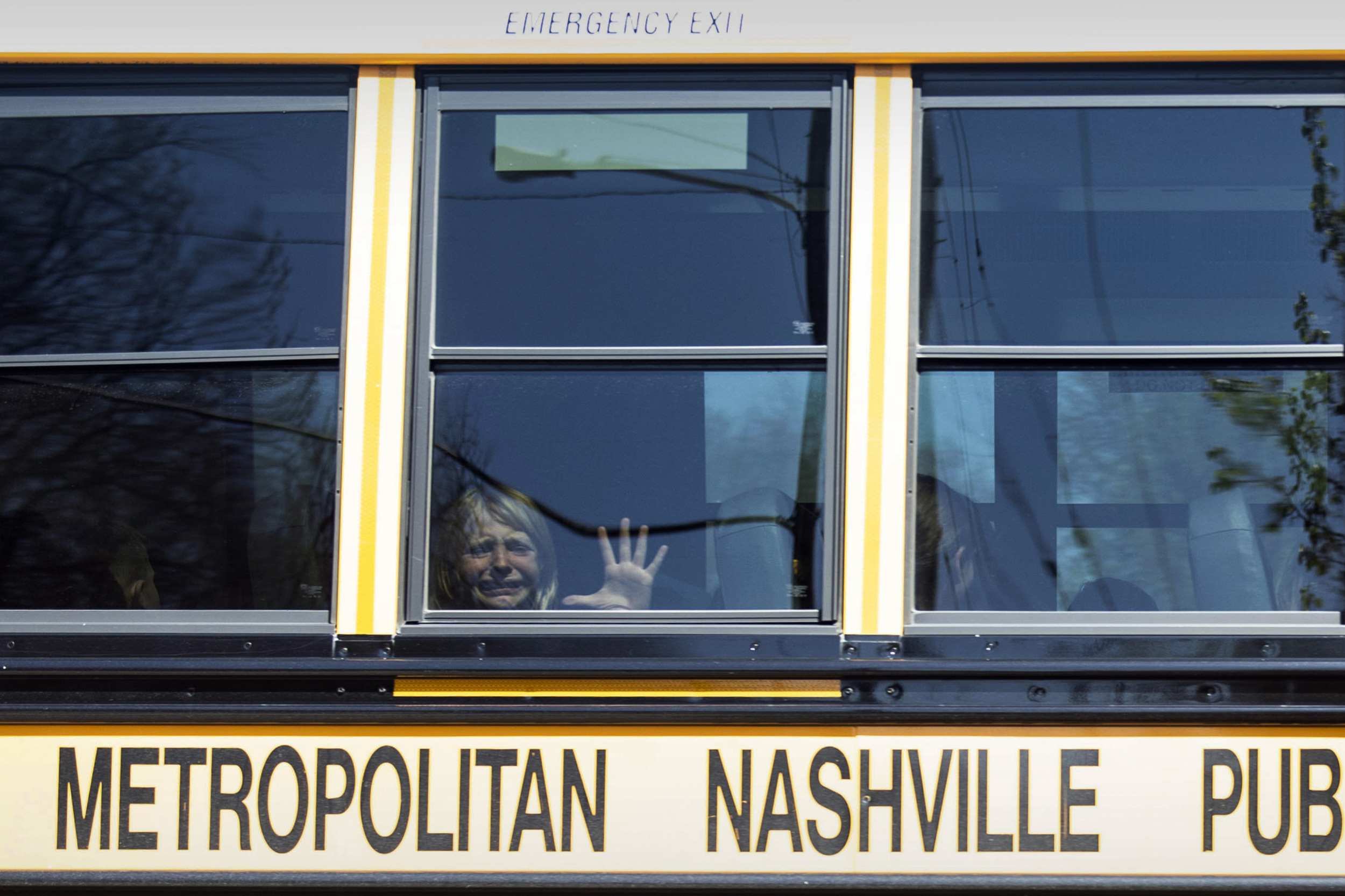 Covenant School shooting: Young blinde girl sits inside yellow school bus with face abd hand pressed against window crying