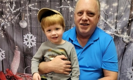 Family First program: older man in blue shirt holding smiling child wearing hat on lap